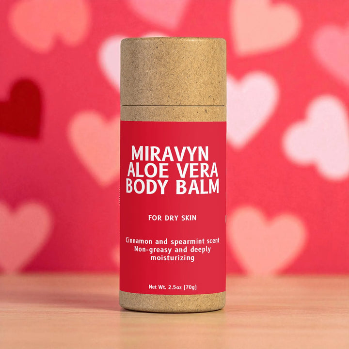 Miravyn Aloe Vera Body Balm container with a red label on a wooden surface and heart-patterned background.