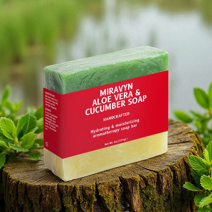 Miravyn Aloe Vera & Cucumber Soap on a wooden log with greenery in the background.