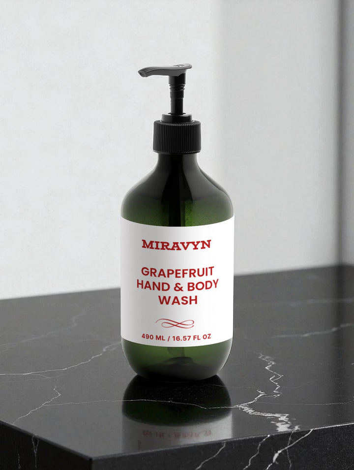 Green bottle of Miravyn Grapefruit Hand & Body Wash on a black marble surface with a white background.