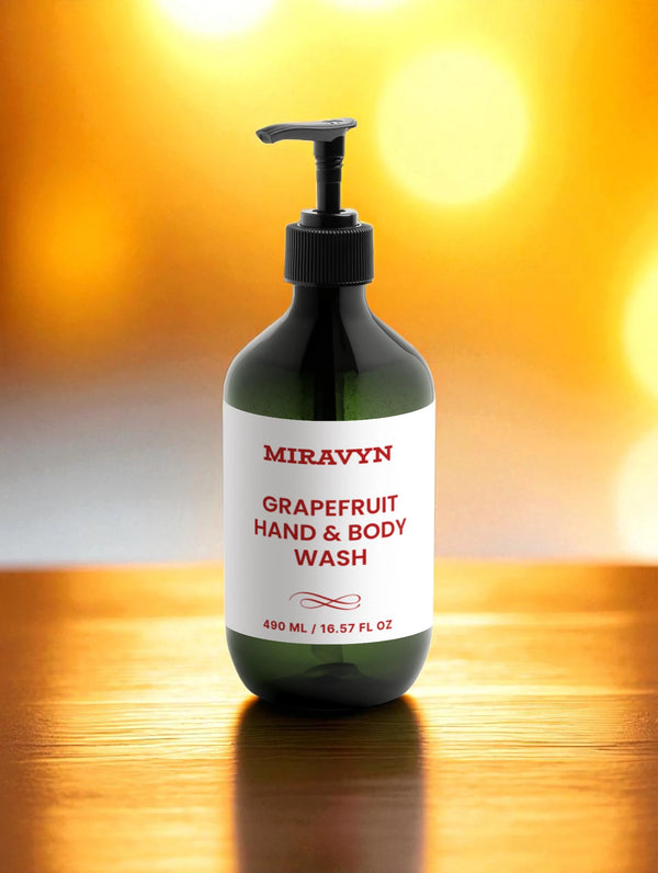Green bottle of Miravyn Grapefruit Hand & Body Wash on a wooden surface with a blurred yellow background.
