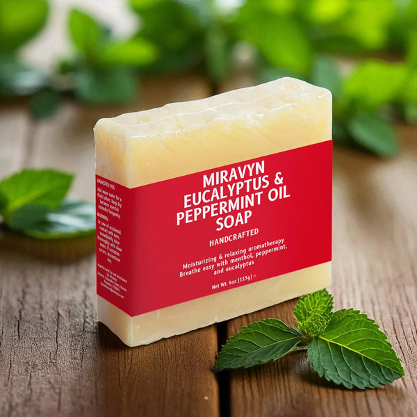 Bar of Miravyn Eucalyptus & Peppermint Oil Soap on a wooden surface with green leaves.