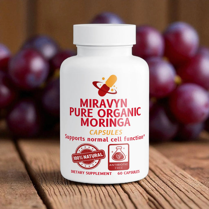 Miravyn Pure Organic Moringa capsules bottle on a wooden surface with grapes in the background.