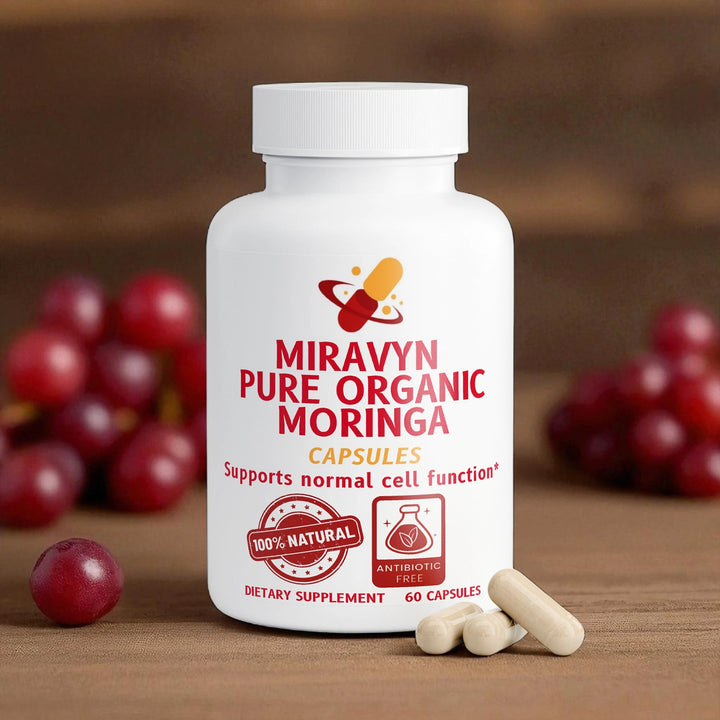 Miravyn Pure Organic Moringa supplement bottle with capsules and grapes on a wooden surface.