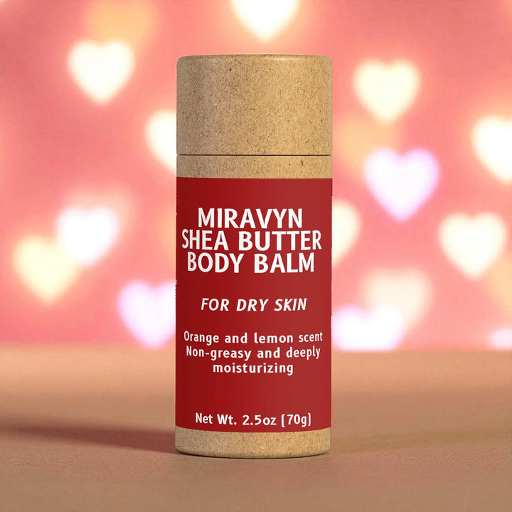 Miravyn Shea Butter Body Balm container with a red label on a blurred heart-patterned background.