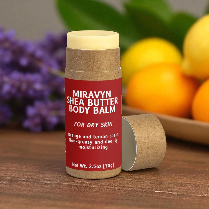 Miravyn Shea Butter Body Balm on a wooden surface with oranges and lavender in the background.