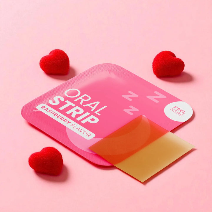 Pink packaging of an oral sleep strip with a yellow strip inside, on a pink background with red heart-shaped objects.
